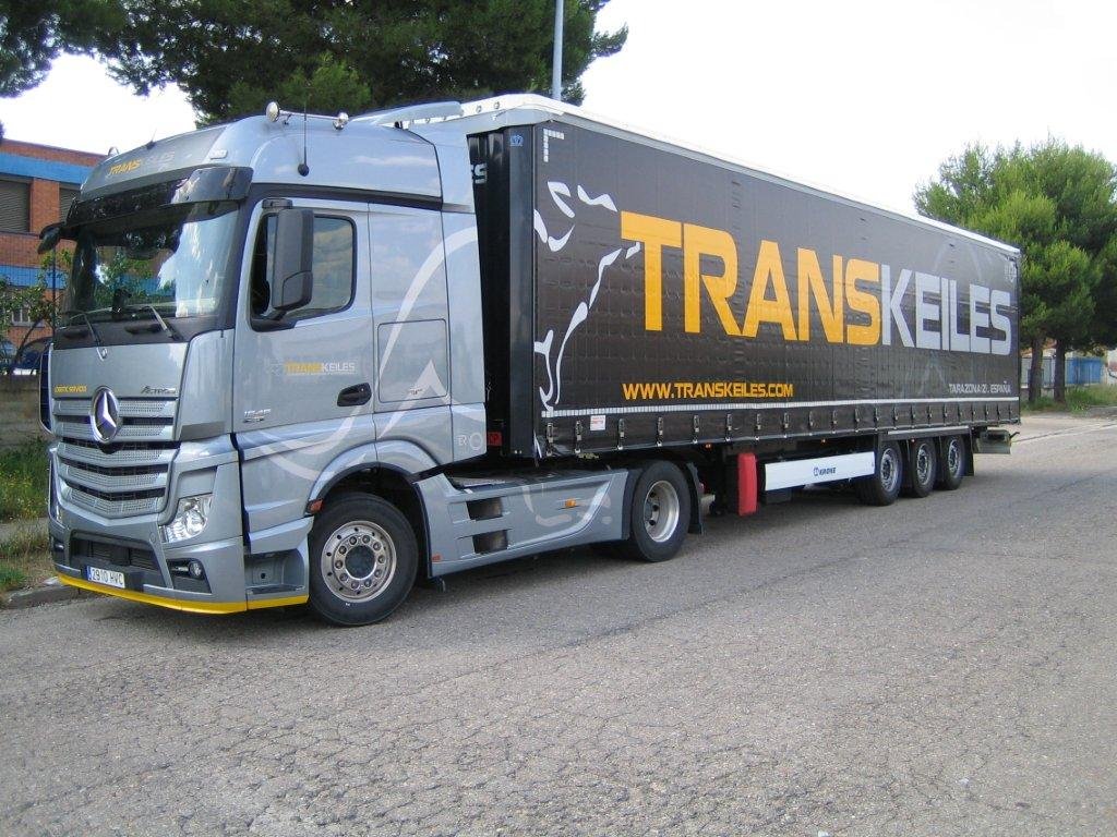 Tractora plateada con semirremolque negro rotulado con la marca Transkeiles, aparcada en una explanada